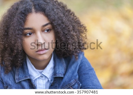 Beautiful mixed race African American girl teenager female young woman outside in autumn or fall looking sad depressed or thoughtful