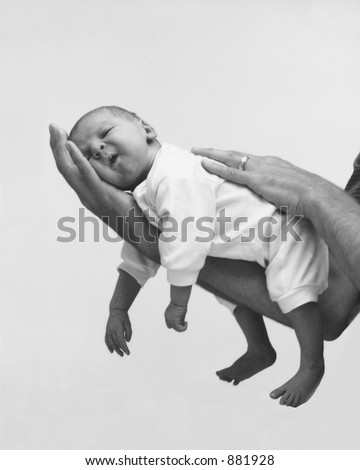 Black and white shot of a small baby resting on his father\'s hand  (Noise visible)