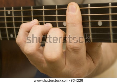 Close up shot of a chord on the fret board of an acoustic guitar