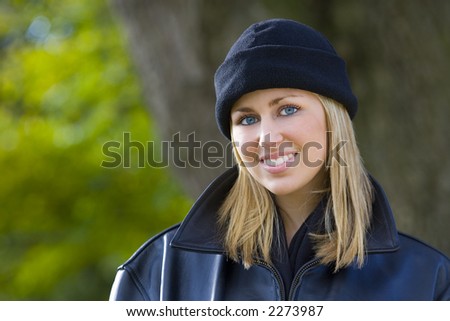 A beautiful young blonde woman with blue eyes wrapped up warm and bathed in winter sunshine