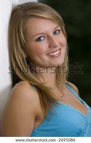 A beautiful young woman leaning in a doorway and sweetly smiling