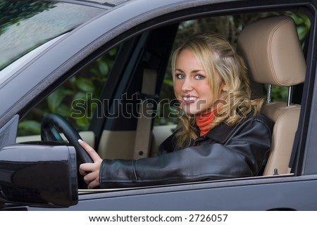 A beautiful young woman driving an expensive black 4 x 4 vehicle