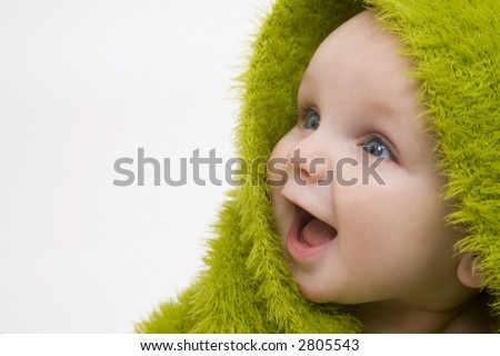 stock photo : A beautiful smiling baby wrapped in a furry green blanket or towel