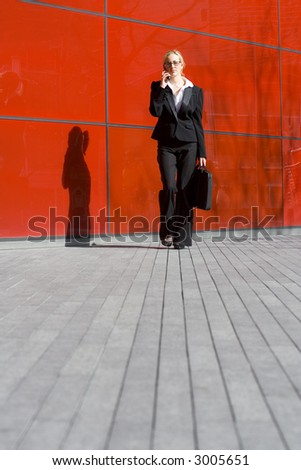 A beautiful young business woman talking on her phone in front of a hi tech office building