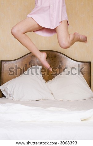 A young woman jumps excitedly on a double bed