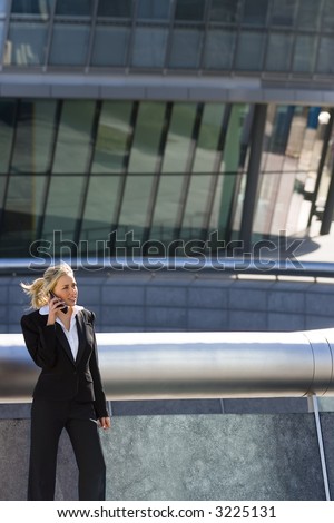 A beautiful young blond executive using a mobile phone in a hi-tech surrounding.