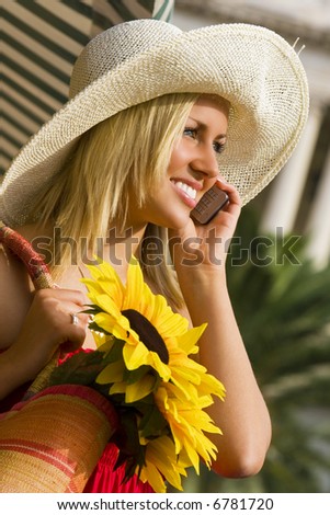 A beautiful young woman bathed in sunshine and making a call on her cell phone