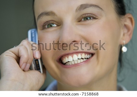 A beautiful dark haired woman talks happily on her mobile phone.