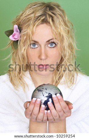 A beautiful young woman with blue eyes holds a globe while looking concerned - shot with a green background that could be used to convey green issues or relatively easily separated and replaced
