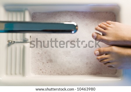 A pair of feet resting on the edge of a foot bath