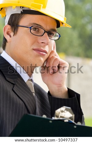 A young male manager in hard hat making a phone call