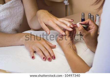 A young woman getting her nails painted during a manicure