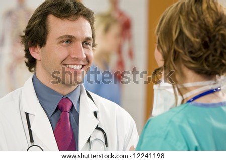 A male consultant talking with his female surgical colleague with other medical staff out of focus in the background