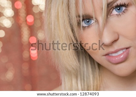 Studio shot of a stunningly beautiful young blond woman shot against a red and gold shimmering background