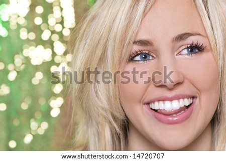 A stunningly beautiful young blond woman with a gorgeous toothy laugh shot against a sparkling green background