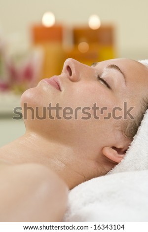A young woman relaxing at a health spa with candles creating a warm and calming atmosphere