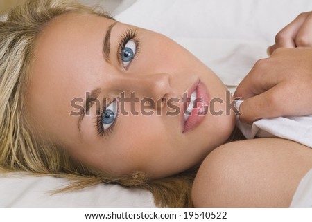  beautiful young blond woman with piercing blue eyes lays in bed