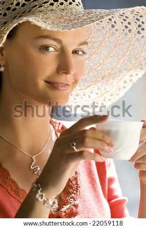 A beautiful young woman with stunning green eyes enjoys a cup of coffee illuminated by natural sunlight