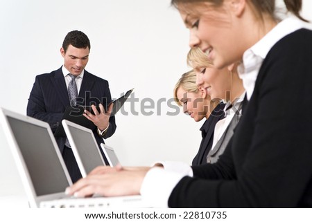 A businessman and his three female colleagues taking part in a happy business meeting. The focus is on the man leading the meeting.