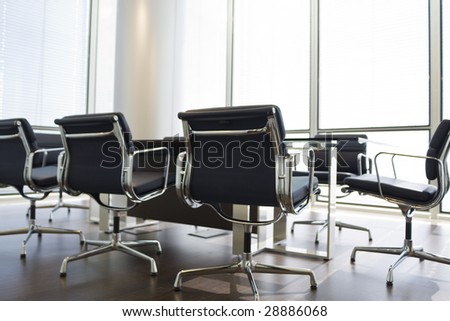 An empty boardroom in a modern office building, the focus is on the chair on the foreground.
