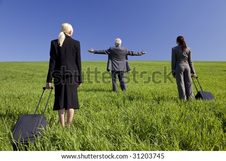 Concept shot showing three business executives, one male and two female, walking through a green field towards the horizon. Environmental, business and travel concepts, shot on location.
