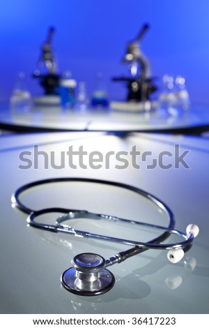 A stethoscope in a medical research laboratory with microscopes, flasks and other equipment in the background