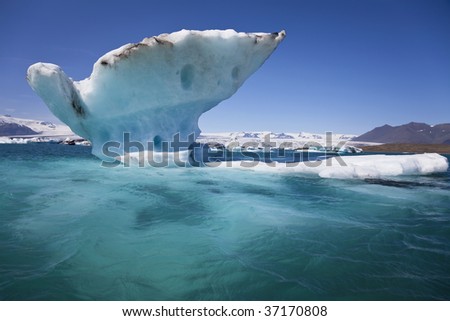A melting glacial iceberg floating on the Iceberg Lagoon, Jokulsarlon, Iceland the drips of melt water can be seen coming off the iceberg.