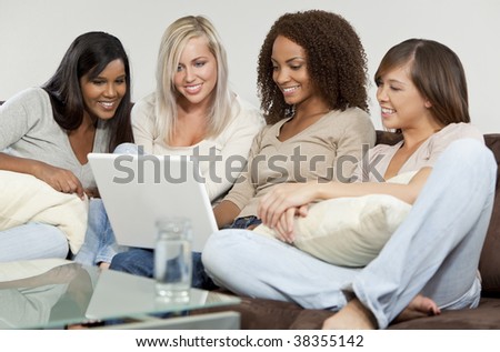 Four mixed race girls, one African American, one Indian, one Asian and one caucasian all having fun using a white laptop computer