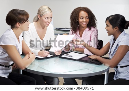 Four women having a business meeting in an office, one African American, one Chinese Asian, One Indian Asian and one Caucasian