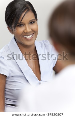 A beautiful young Asian businesswoman with a wonderful smile in a meeting with her colleague out of focus in front of her.