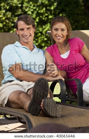 Portrait shot of an attractive, successful and happy middle aged man and woman couple in their thirties, sitting together holding hands and smiling.