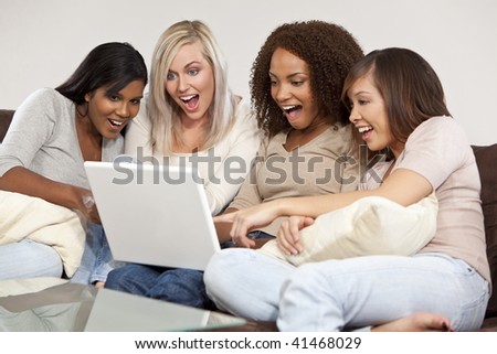 A group of four interracial beautiful young women having fun looking at something surprising and funny on their laptop computer and laughing