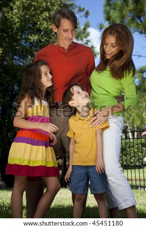 A modern family of father, mother, daughter and son playing together and having fun in a park