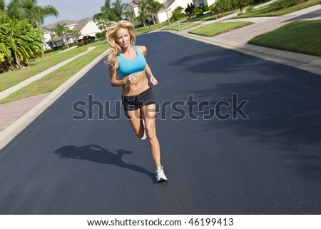 A beautiful fit and healthy blond woman road running down a suburban street in summer sunshine
