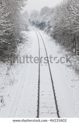 Snow covered railway tracks curving away around a corner into the distance