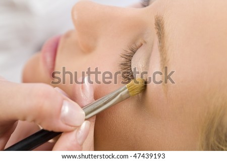 A beautiful young woman having her make up applied by a beautician in health spa.