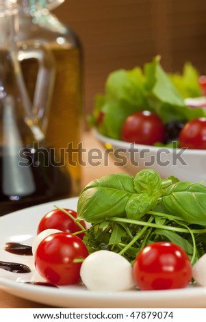 Tomato, mozzarella, rocket salad with olive oil and balsamic vinegar dressing and basil garnish shot in golden sunshine