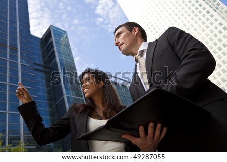 A smiling Indian Asian businesswoman and her male colleague taking part in a happy business meeting outside in a modern city environment