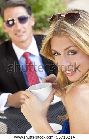 A beautiful and sophisticated young woman having coffee at a modern city cafe table with her friend a smart dressed businessman