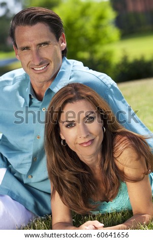 Portrait shot of an attractive, successful and happy middle aged man and woman couple in their thirties, sitting together outside and smiling.