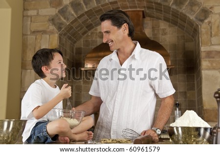 An attractive smiling father and son cooking baking chocolate chip cookies in a kitchen at home