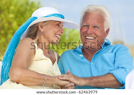 Happy senior man and woman couple having fun together holding hands and laughing on a deserted tropical beach.