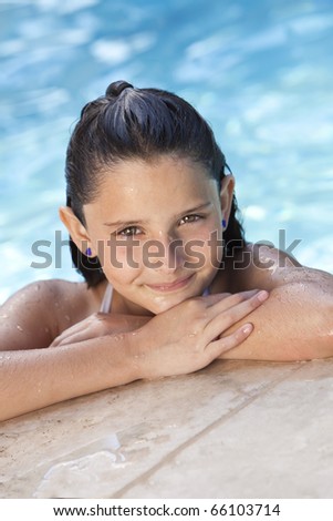 A cute happy young girl child relaxing on the side of a swimming pool