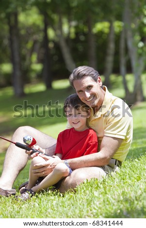 A father teaching his son how to fish on a river outside in summer sunshine