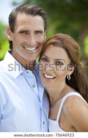 Portrait shot of an attractive, successful and happy middle aged man and woman couple in their thirties, together outside and smiling.