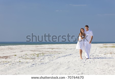 Man and woman romantic couple in white clothes walking and laughing together on a deserted tropical beach with bright clear blue sky