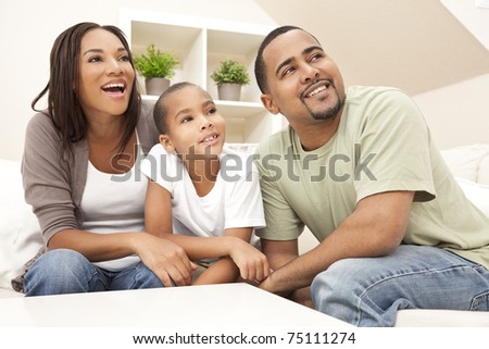 Happy African American family, parents and son, sitting on a sofa at home laughing and smiling