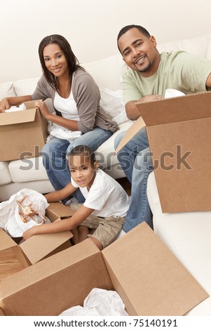 African American family, parents and son, unpacking boxes and moving into a new home, The adults are unpacking crockery and homeware, the child is unpacking a toy airplane.