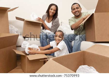 African American family, parents and son, unpacking boxes and moving into a new home, The adults are unpacking crockery, the child is unpacking a toy airplane.