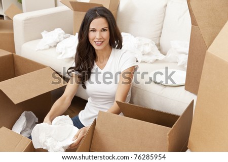 A beautiful single young woman unpacking boxes and moving into a new home.